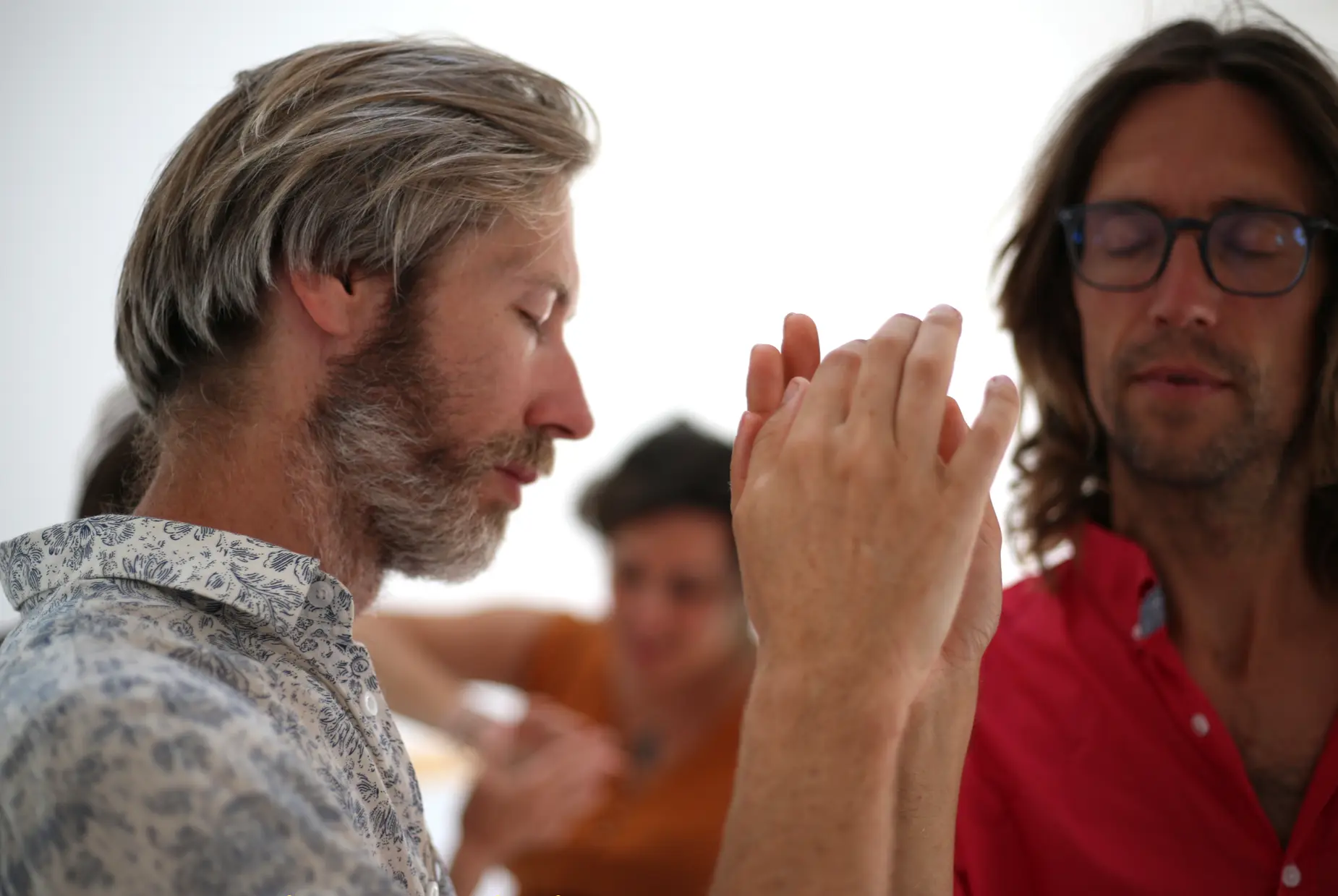 Deux danseurs, les yeux fermés, partagent avec sensibilité une danse avec leurs index réunis lors d’une proposition d’une séance de Biodanza