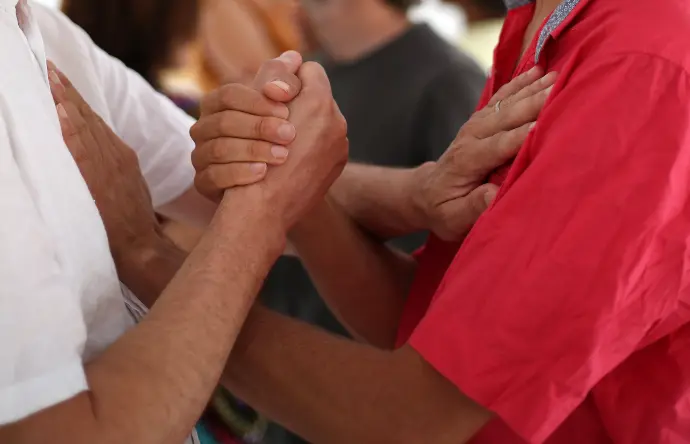 Deux personnes se rencontrent, se dévoilent, se touchent les mains et les posent sur le cœur de l'autre lors d'un cours de Biodanza facilité par Christophe Brumbt à Bédarieux
